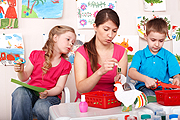 preschool girl and boy with female teacher at crafts table